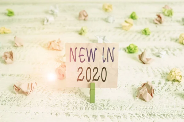 Handwriting text New In 2020. Conceptual photo what will be expecting or new creation for the year 2020 Green clothespin white wood background colored paper reminder office supply