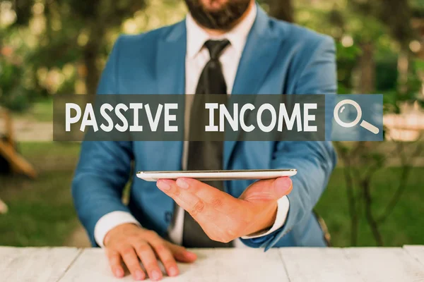 Text sign showing Passive Income. Business photo showcasing the earnings derived from a rental property and others Businessman with mobile phone in his hand