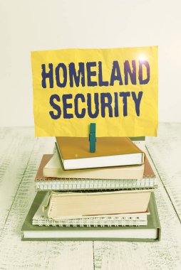 Mesaj işareti İç Güvenlik 'i gösteriyor. ABD 'yi tehditlere karşı korumak için tasarlanmış iş fotoğrafı sergisi federal ajansı yığınla kitap yığını defter mandalı renkli hatırlatıcı beyaz ahşap.