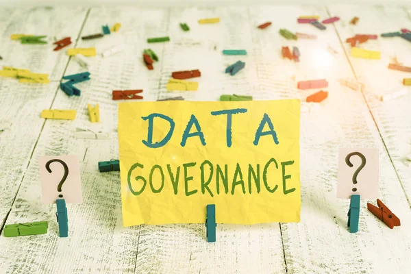 Conceptual hand writing showing Data Governance. Concept meaning general management of key data resources in a company Crumbling sheet with paper clips placed on the wooden table