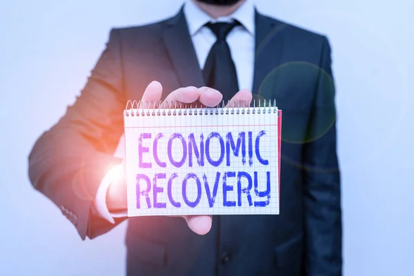 Handwriting text writing Economic Recovery. Concept meaning rise of business activity signaling the end of a recession Male human wear formal work suit office look hold mathematics book use hand. — Stock Photo, Image
