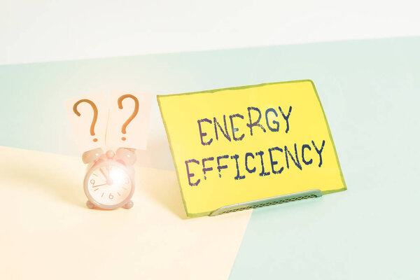 Word writing text Energy Efficiency. Business photo showcasing reduce the amount of energy required to provide product Mini size alarm clock beside a Paper sheet placed tilted on pastel backdrop