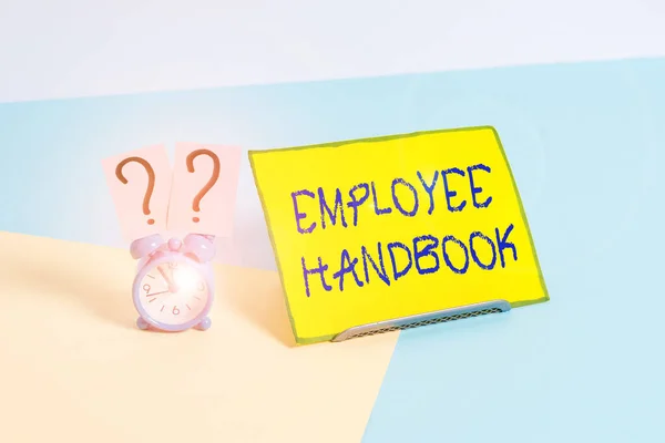 Word writing text Employee Handbook. Business photo showcasing states the rules and regulations and policies of a company Mini size alarm clock beside a Paper sheet placed tilted on pastel backdrop