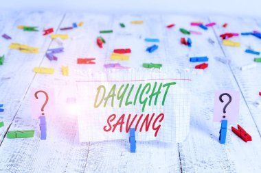 Gün Işığı Tasarruf 'u gösteren not yazıyorum. Sıcak hava yaklaşırken saati ileri almak için kullanılan iş konsepti ahşap masaya raptiye takılmış kırılan çarşaf.