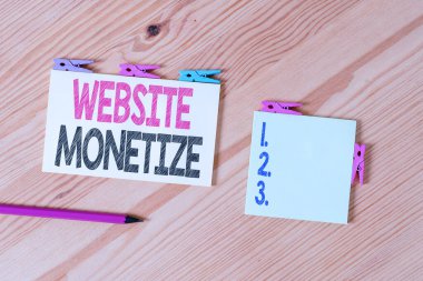 Web sitesi Monetize 'yi gösteren bir not yazıyorum. Yetenek için iş konsepti Web sitenizi ya da blogunuzu ayrıntılı bir şekilde oluşturur Renkli çamaşır iğnesi kağıtları boş hatırlatıcı ahşap zemin ofis