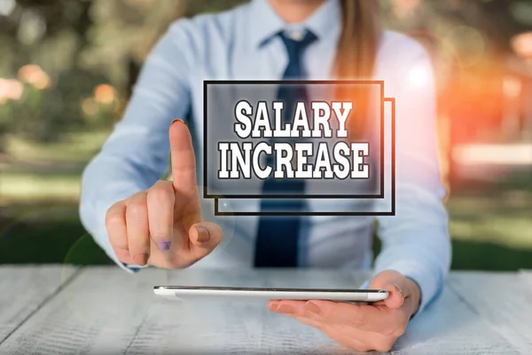 Conceptual hand writing showing Salary Increase. Business photo text an increase in the salary or pay given to an employee Female business person sitting by table and holding mobile phone.