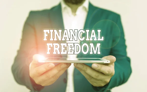 Text sign showing Financial Freedom. Business photo text make big life decisions without being stressed about money Businessman holds laptop in his hand. Man holding mobile phone with touch screen