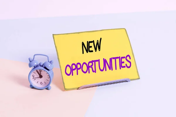 Text sign showing New Opportunities. Business photo showcasing situation that makes it possible to do something Mini size alarm clock beside a Paper sheet placed tilted on pastel backdrop