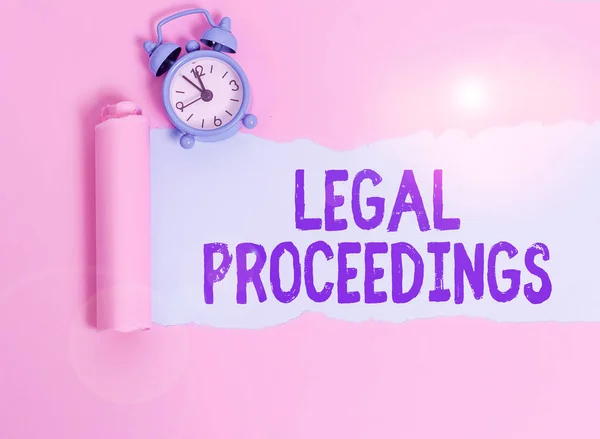 Writing note showing Legal Proceedings. Business concept for procedure instituted in a court of law to acquire benefit Alarm clock and torn cardboard placed above plain pastel table backdrop