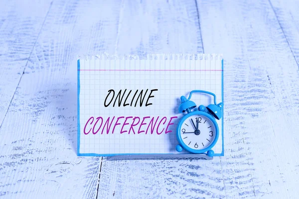 Word writing text Online Conference. Business photo showcasing online service by which you can hold live meetings Mini blue alarm clock stand tilted above buffer wire in front of notepaper