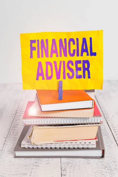 Text sign showing Financial Adviser. Business photo showcasing demonstrating who is employed to provide financial services pile stacked books notebook pin clothespin colored reminder white wooden