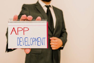 Uygulama Geliştirmesini gösteren kavramsal el yazısı. Bir mobil uygulamanın geliştirildiği eylem ya da süreç anlamına gelen kavram: Erkek insan resmi iş elbisesi ve ofis tutucu kitap