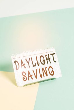 Yaz tabelası Yaz Saati 'ni gösteriyor. İş fotoğrafı metni, sıcak hava yaklaştıkça saati öne alıyor. Tampon tellerin üzerine yerleştirilmiş kağıt, yumuşak pastel çok renkli arka planda.