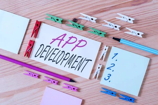 Word writing text App Development. Business concept for the act or process by which a mobile app is developed Colored clothespin papers empty reminder wooden floor background office.
