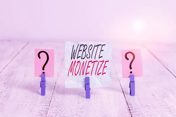 Writing note showing Website Monetize. Business concept for ability generate a revenue thorough your Web site or blog Crumbling sheet with paper clips placed on the wooden table