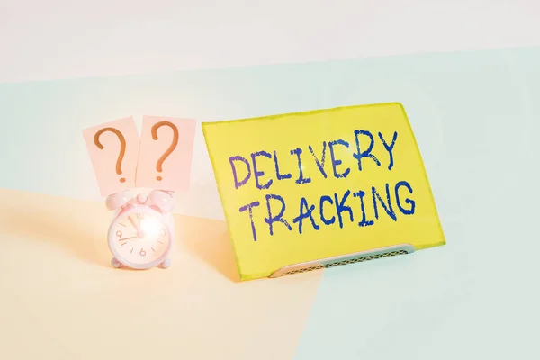 Word writing text Delivery Tracking. Business photo showcasing the process of localizing shipping containers and mails Mini size alarm clock beside a Paper sheet placed tilted on pastel backdrop