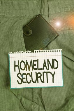 Kelime yazma İç Güvenlik 'e mesaj attı. ABD 'yi tehditlere karşı korumak için tasarlanmış iş fotoğrafı sergisi federal ajansı. Not kağıdının yanındaki cepteki küçük cüzdan.