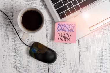 Business Travel 'ı gösteren bir not yazıyorum. Bir ya da daha fazla yere şirket adına fotoğraf sergisi gezisi. Trendi metalik dizüstü bilgisayar. Boş, yapışkan kahve fincanı faresi..