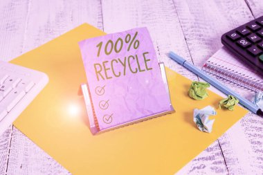 El yazısı% 100 Geri Dönüşüm. Kavramsal fotoğraf, bilgisayar klavyesi ve matematik sayfaları arasındaki tampon telin üzerinde bulunan% 100 'lük bir tüketici sonrası not kağıdı duruşu içerir.