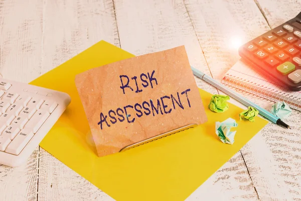 Writing note showing Risk Assessment. Business concept for estimation of the levels of risks involved in a situation Notepaper on wire in between computer keyboard and sheets