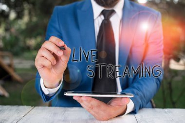 Conceptual hand writing showing Live Streaming. Concept meaning media simultaneously recorded and broadcast in real time Businessman pointing with pen in empty copy space