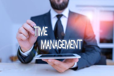 Zaman Yönetimini gösteren bir not yazıyorum. Bir zamanı etkili ya da üretken bir şekilde kullanabilme yeteneği için iş konsepti mevcut erkek kıyafetleri giyin Hitech akıllı telefonu kullanın