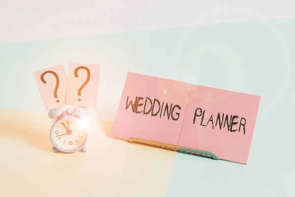 Word writing text Wedding Planner. Business concept for someone who plans and organizes weddings as a profession Mini size alarm clock beside a Paper sheet placed tilted on pastel backdrop.