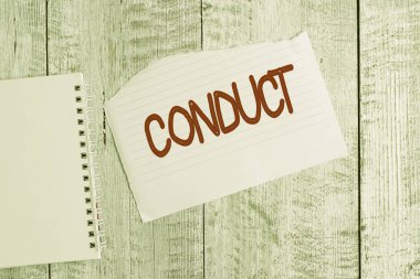 Conceptual hand writing showing Conduct. Business photo text manner in which an organization or activity is managed or directed Torn paper and notebook sheet placed above classic wooden table.