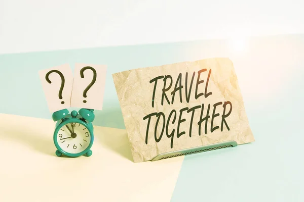 Word writing text Travel Together. Business concept for opportunities to learn and grow together in an adventure Mini size alarm clock beside a Paper sheet placed tilted on pastel backdrop.