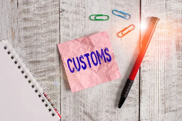 Word writing text Customs. Business concept for Official department administers collects duties on imported goods Wrinkle paper and notebook plus stationary placed above wooden background.