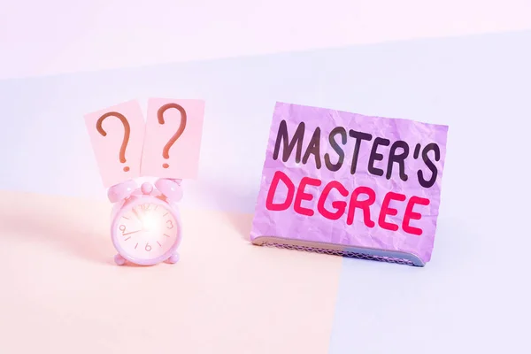 Handwriting text Master S Degree. Concept meaning degree that is given to a student by a college or university Mini size alarm clock beside a Paper sheet placed tilted on pastel backdrop.