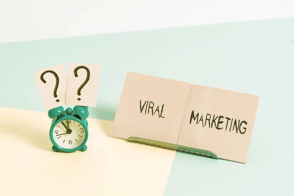 Word writing text Viral Marketing. Business concept for spreading information and opinions about a product Mini size alarm clock beside a Paper sheet placed tilted on pastel backdrop.