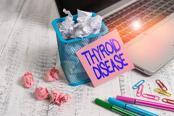 Word writing text Thyroid Disease. Business concept for the thyroid gland fails to produce enough hormones Laptop sticky note waste basket crushed paper ball clips pens vintage table.