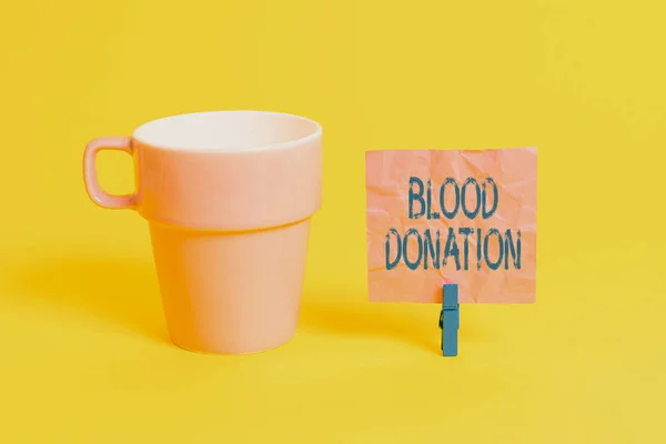Text sign showing Blood Donation. Conceptual photo Process of collecting testing and storing whole blood Cup empty paper blue clothespin rectangle shaped reminder yellow office. — Stockfoto