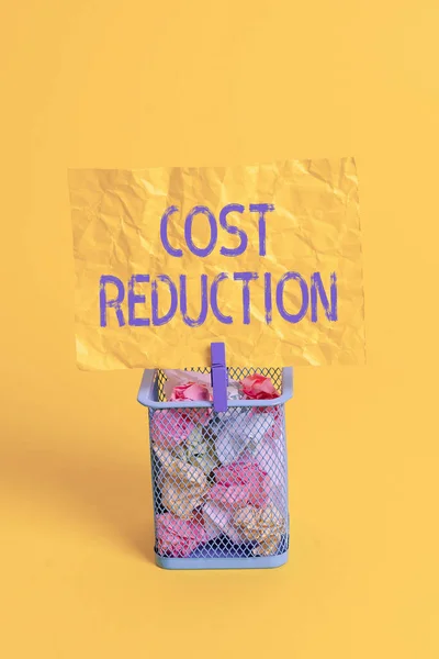 Text sign showing Cost Reduction. Conceptual photo process of finding and removing unwarranted expenses Trash bin crumpled paper clothespin empty reminder office supplies yellow.