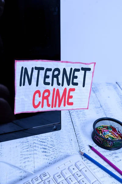 İnternet Suçları 'ndan el yazısı. Konsept, klavye yakınındaki siyah bilgisayar ekranına bantlanmış internet not kağıdında suç veya yasadışı çevrimiçi faaliyet anlamına gelir.