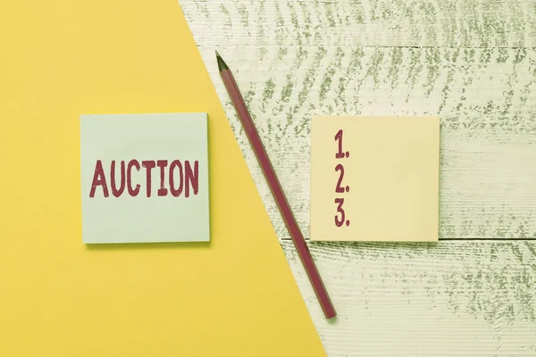 Conceptual hand writing showing Auction. Business photo showcasing Public sale Goods or Property sold to highest bidder Purchase Blank notepads pen colored paper sheet wooden background. — Stockfoto