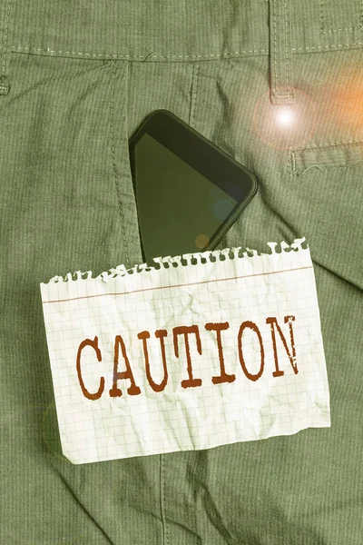 Texto para escrita de palavras Cuidado. Conceito de negócio para Cuidado para evitar perigos ou erros Sinal de alerta Prevenção Dispositivo Smartphone dentro de calças de trabalho formais bolso frontal perto de papel de nota . — Fotografia de Stock