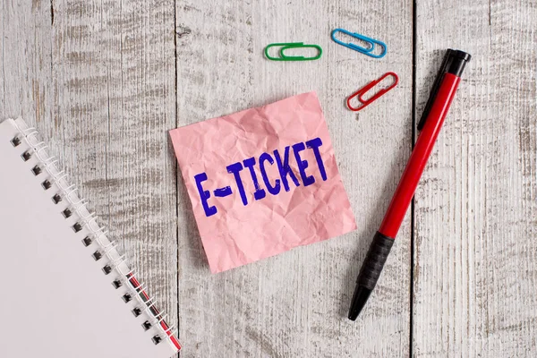 Pisanie tekstu E Ticket. Koncepcja biznesowa biletu cyfrowego, który jest ważny jak bilet papierowy lub równoważny papier i notatnik do zmarszczek plus stacjonarny umieszczony nad drewnianym tłem. — Zdjęcie stockowe