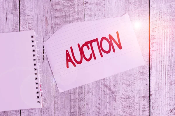 Conceptual hand writing showing Auction. Business photo text Public sale Goods or Property sold to highest bidder Purchase Torn paper and notebook sheet placed above classic wooden table.