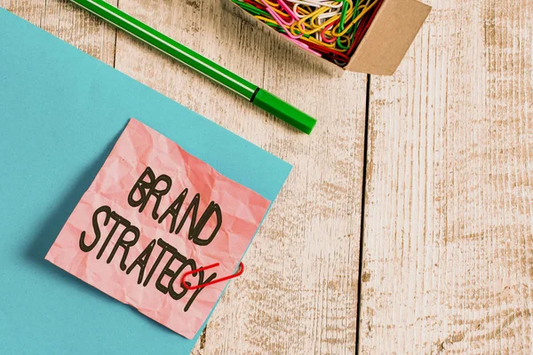 Writing note showing Brand Strategy. Business photo showcasing Longterm plan for the development of a successful brand Wrinkle paper and cardboard placed above wooden background.