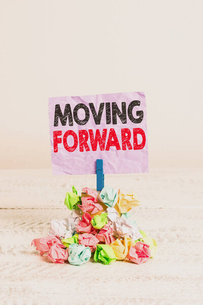 Writing note showing Moving Forward. Business photo showcasing Toward or at a place point or time in advance Onward Ahead Reminder pile colored crumpled paper clothespin wooden space.