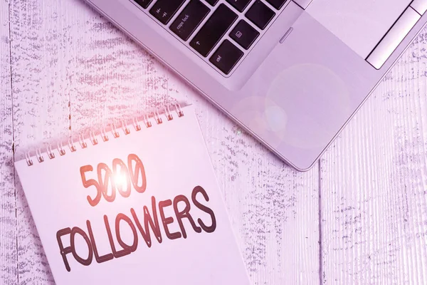 Γραπτό σημείωμα που δείχνει 5000 οπαδούς. Business photo showcasing number of individuals who follows someone in Instagram Κορυφαία μοντέρνα μεταλλική φορητό υπολογιστή κενό σπιράλ σημειωματάριο που βρίσκεται σε ξύλινο τραπέζι. — Φωτογραφία Αρχείου