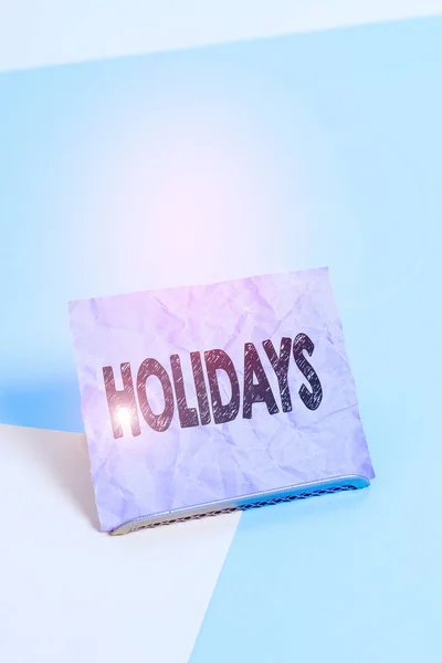 Handwriting text Holidays. Concept meaning an extended period of leisure and recreation spent away from home Paper placed tilted above buffer wire on soft pastel multi colours backdrop. — Stock Photo, Image