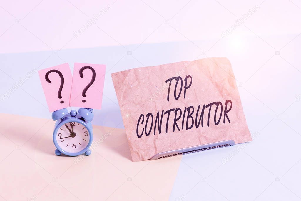 Word writing text Top Contributor. Business concept for demonstrating who is knowledgeable in a particular category Mini size alarm clock beside a Paper sheet placed tilted on pastel backdrop.