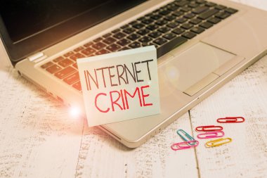 İnternet Suçları 'ndan el yazısı. Kavram, suç ya da yasadışı online faaliyet anlamına gelir İnternet Trendy metalik laptop boş yapışkan ped klipleri yalan ahşap eski masa.