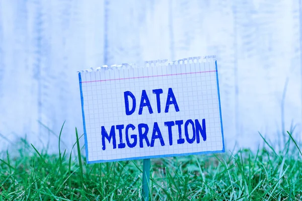 Word writing text Data Migration. Business concept for process of transferring data between data storage systems Mathematic paper attached to a stick and placed in the green grassy land.