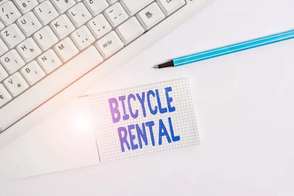 자전거 렌트를 보여 주는 문자 표지판. 개념 사진 관광객이나 여행자에게 자전거를 렌더링하는 비즈니스 사진 흰색 배경 위에 빈 노트 종이가 있는 흰색 PC 키보드. — 스톡 사진