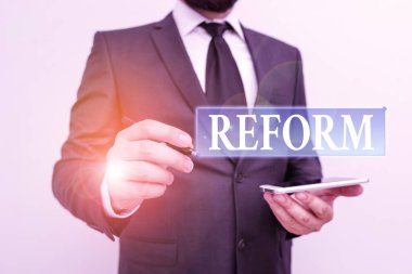 Handwriting text writing Reform. Concept meaning to amend or improve by change of forms or removal of faults Male human wear formal work suit hold smart hi tech smartphone use one hand.