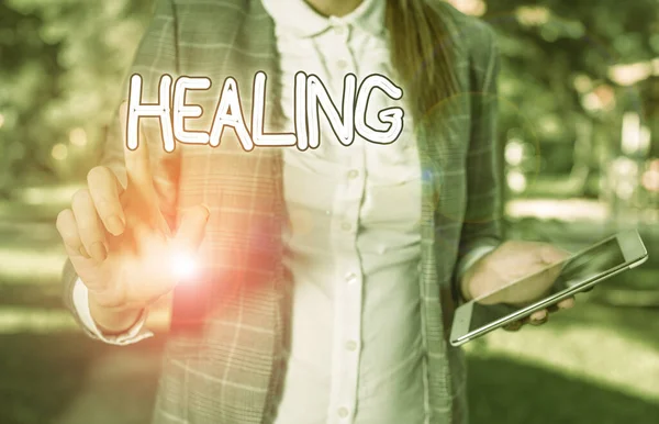 Conceptual hand writing showing Healing. Business photo showcasing process of making or becoming sound or healthy again Helping injured Business woman sitting with mobile phone and cup of coffee. — Stok fotoğraf